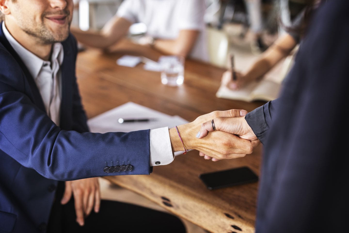 business handshake in office VYYYLWL e1650789239773