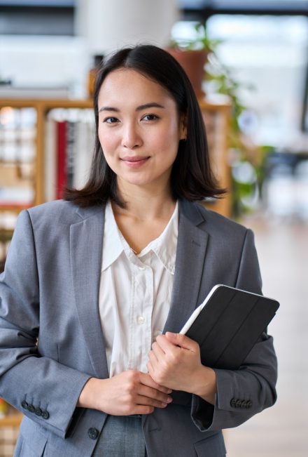 smiling young asian business woman standing in off